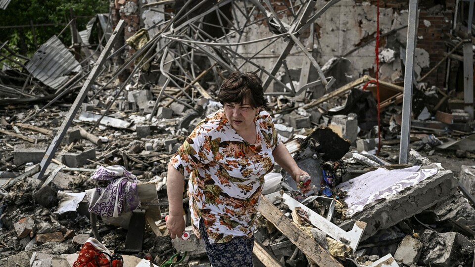Une femme au milieu des décombres d'une habitation. 