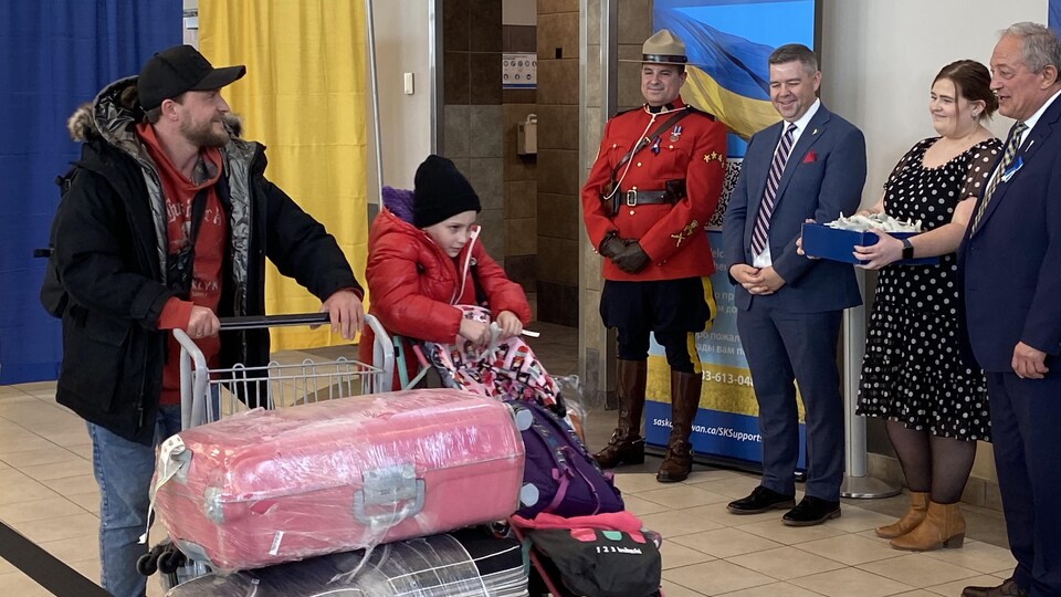 Un réfugié ukrainien pousse un chariot rempli des valises à l'aéroport de Regina.
