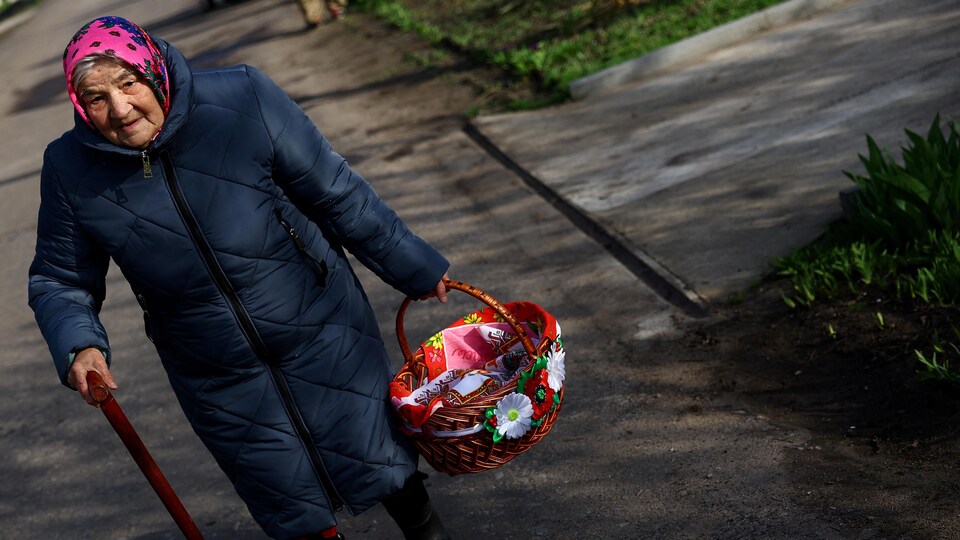 Une dame âgée marche avec un panier de provisions.