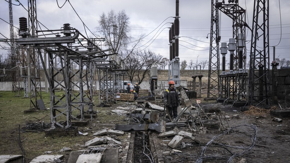 Un homme debout au milieu d'une installation électrique détruite