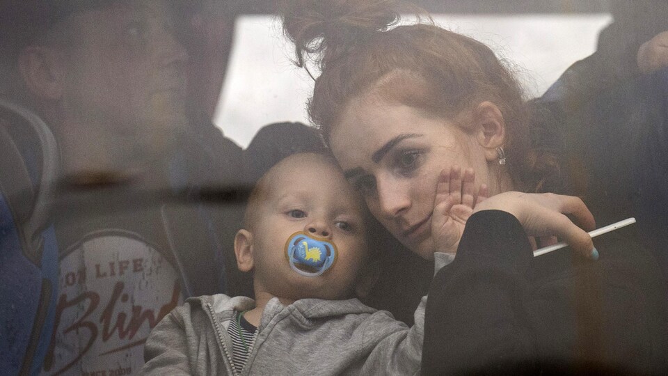 Une femme tient son bébé dans un bus alors qu'ils quittent Kiev, en Ukraine, le jeudi 24 février 2022. 