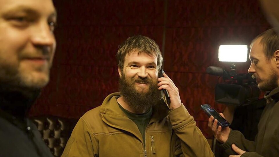 Un homme parle au téléphone au milieu de deux hommes.