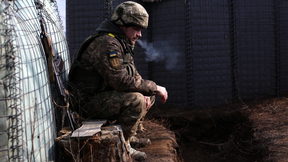 Un homme en treillis militaire fume.