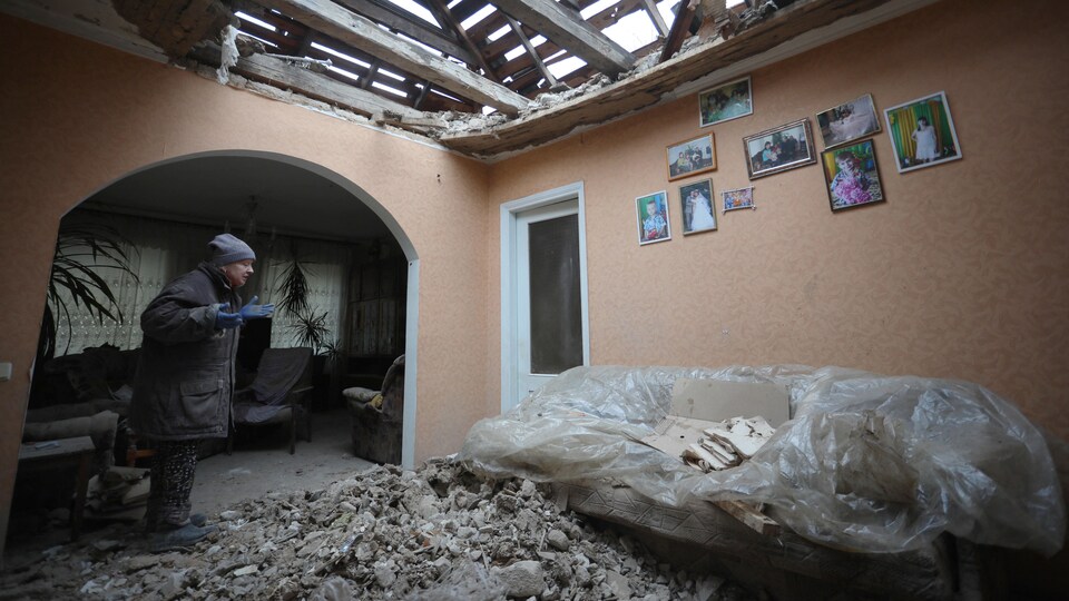 Une femme dans une maison endommagée par des bombardements.