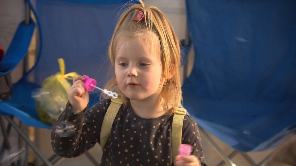 Little Nicole blows bubbles into the air, which are made of soap and water.
