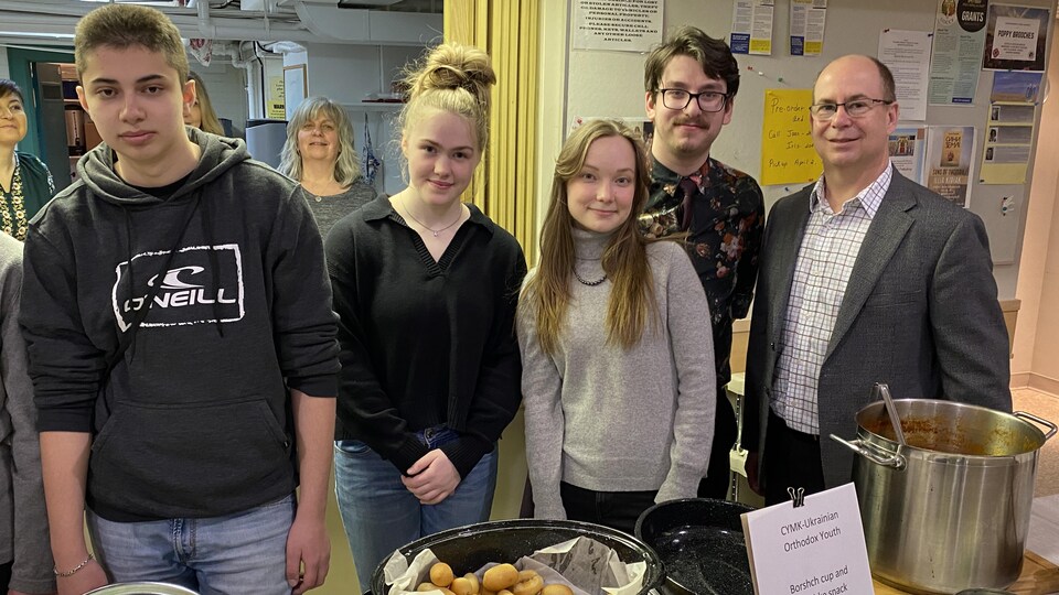Plusieurs personnes se tiennent devant un kiosque de plats traditionnels ukrainiens lors d'un marché de produits artisanaux ukrainiens à Winnipeg.