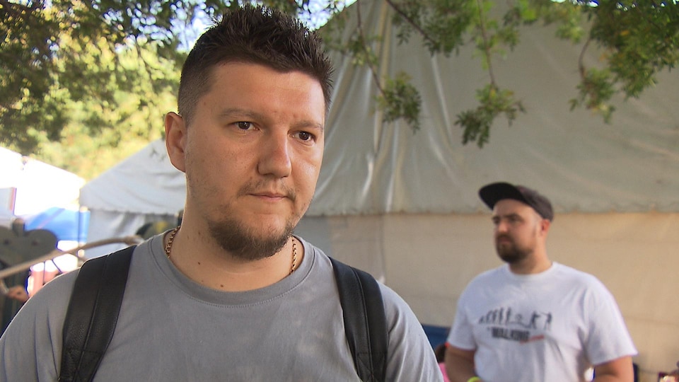 Nikita, carrying a backpack, answers questions from journalist Frédéric Arnould.