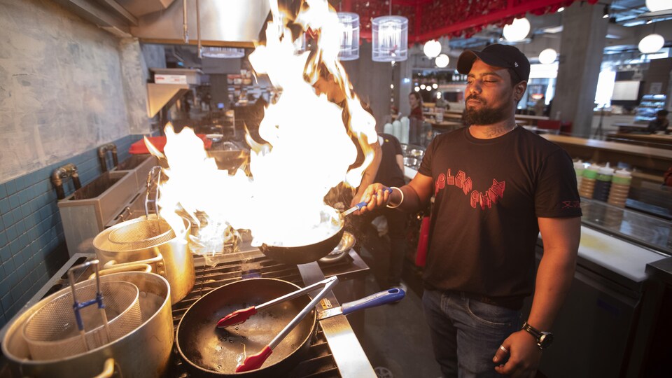 Un cuisinier maniant une poêle en feu.