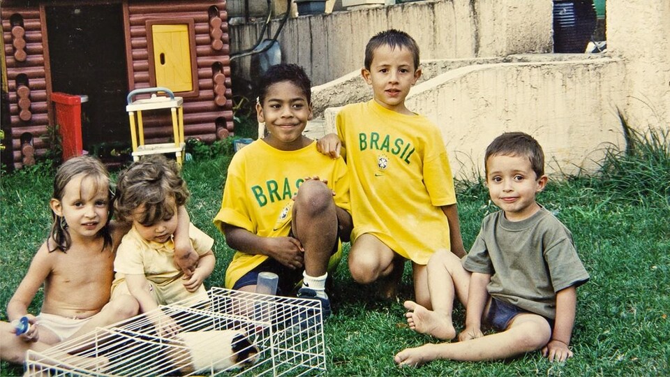 Cinq enfants assis dans une cour regardent la caméra.