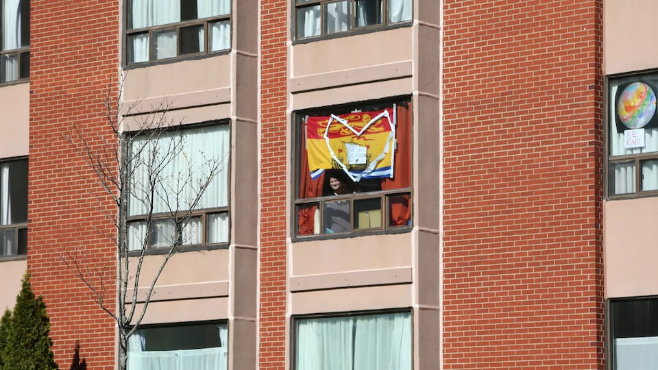 Une étudiante regarde par la fenêtre sur laquelle a été installé un coeur.