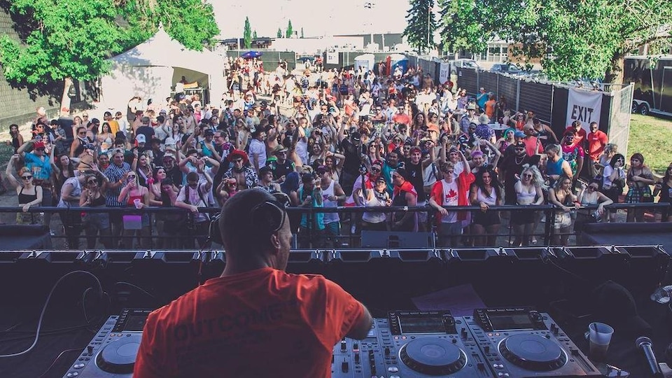 Un DJ joue devant une foule en extérieur.