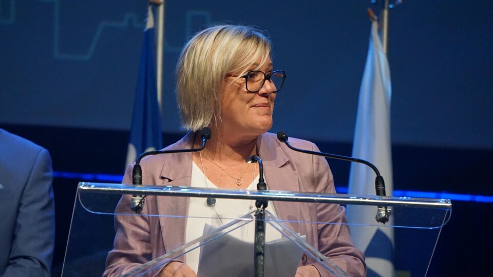 Cathy Pourier spricht auf der Bühne hinter einer Konzertbühne. 