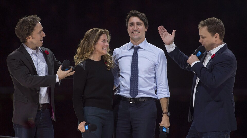 Quatre personnes sur scène lors d'un événement public.