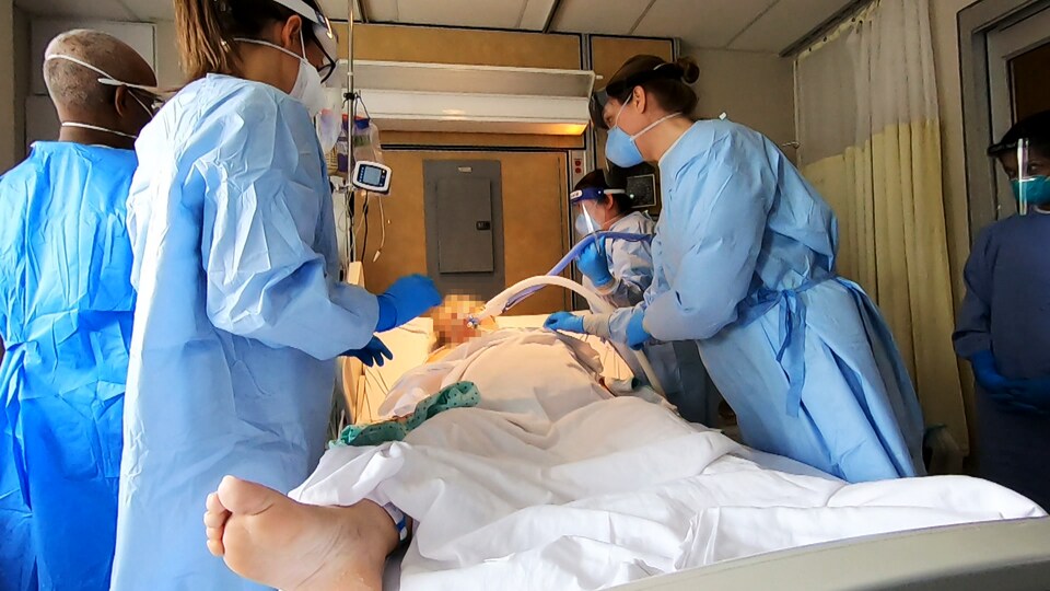 Cinq professionnels de la santé encerclent un patient intubé sur un lit d'hôpital.