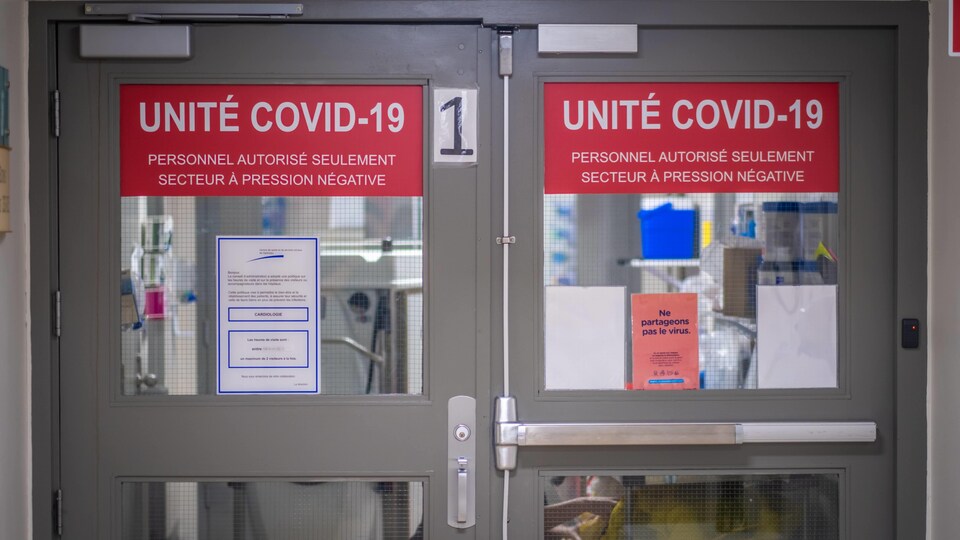Des portes battantes dans un hôpital indiquant Unité COVID-19.