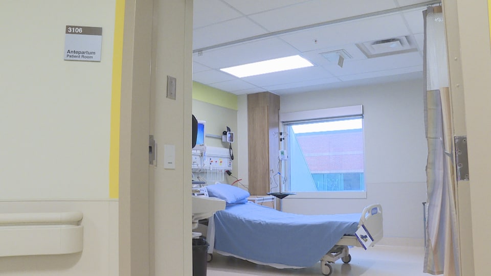 Vue de l'intérieur d'un chambre d'hôpital, meublée d'un lit. Un panneau indique à l'entrée qu'il s'agit d'une chambre de traitement pré-accouchement.