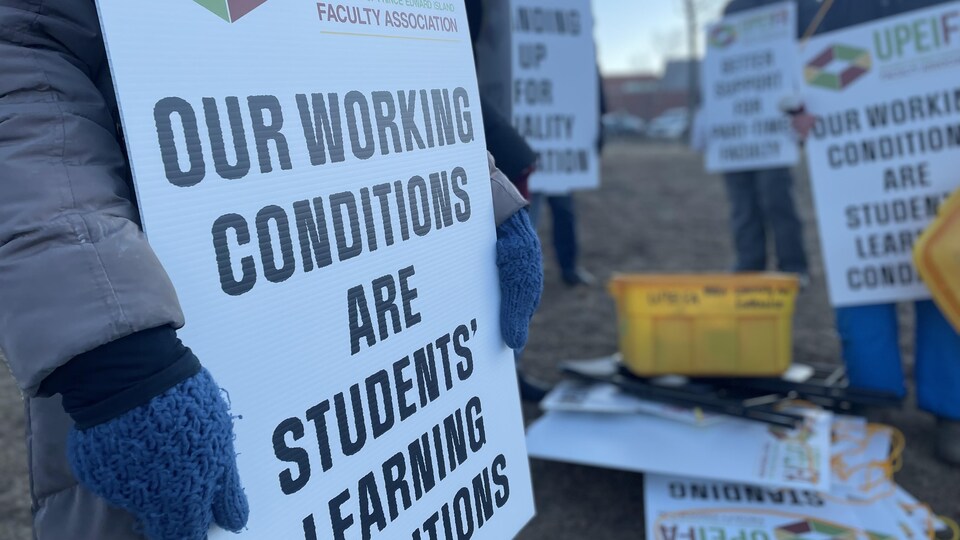 Les pancartes des grévistes portent des messages au sujet des conditions de travail à améliorer.
