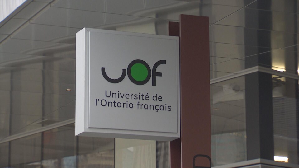Affiche près d'un immeuble sur lequel on peut lire UOF, Université de l'Ontario français.