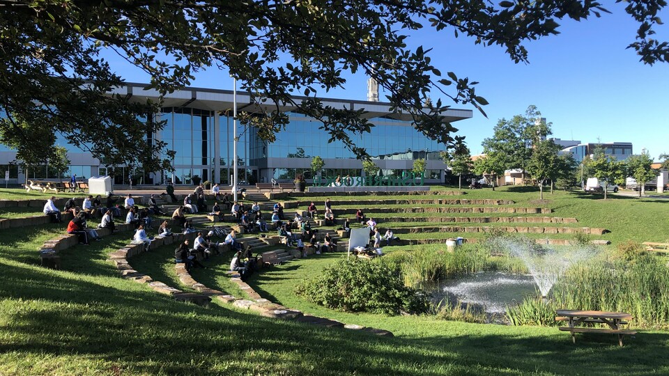 Des étudiants suivent un cours dans un amphithéâtre extérieur.