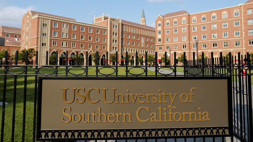 Clôture à l'entrée de l'université et une affiche sur laquelle on peut lire : « USC University of Southern California ».