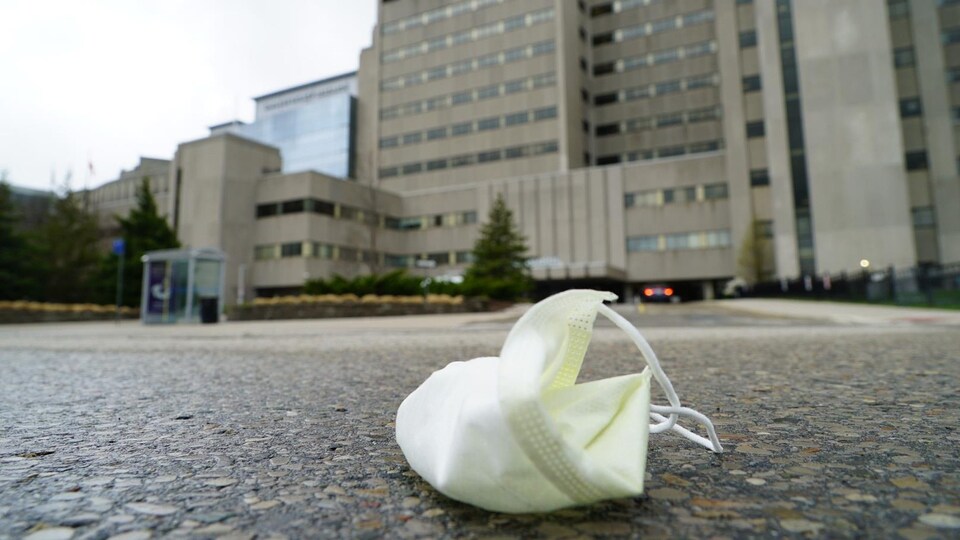 Un masque jeté sur la chaussée devant un hôpital.