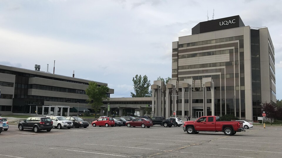 Des véhicules sont garés à proximité de deux pavillons de l'Université du Québec à Chicoutimi