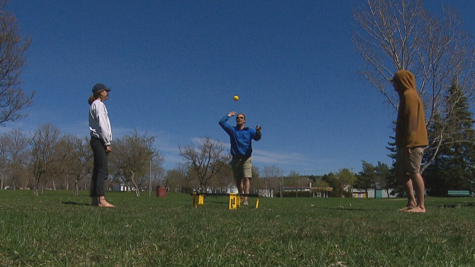 Trois personnes jouent au Spikeball dans un parc.