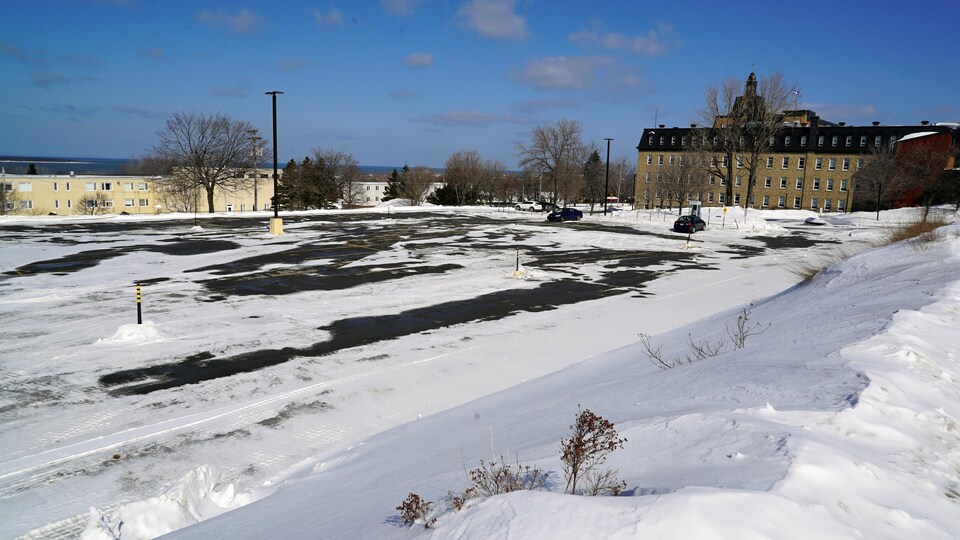 Le stationnement de l'université est quasi désert sous la neige.