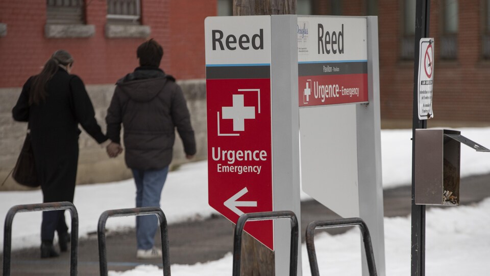 Une femme et un homme, de dos, marchent près de l'entrée de l'urgence.
