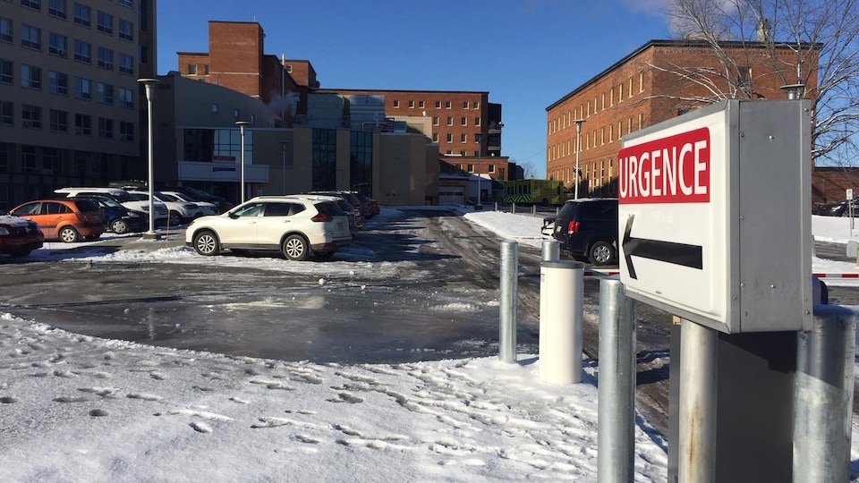 Le stationnement d'un hôpital est remplis alors qu'une vague de froid déferle sur le Québec. La chaussée est glacée et les déplacements vers l'entrée sont difficiles. 