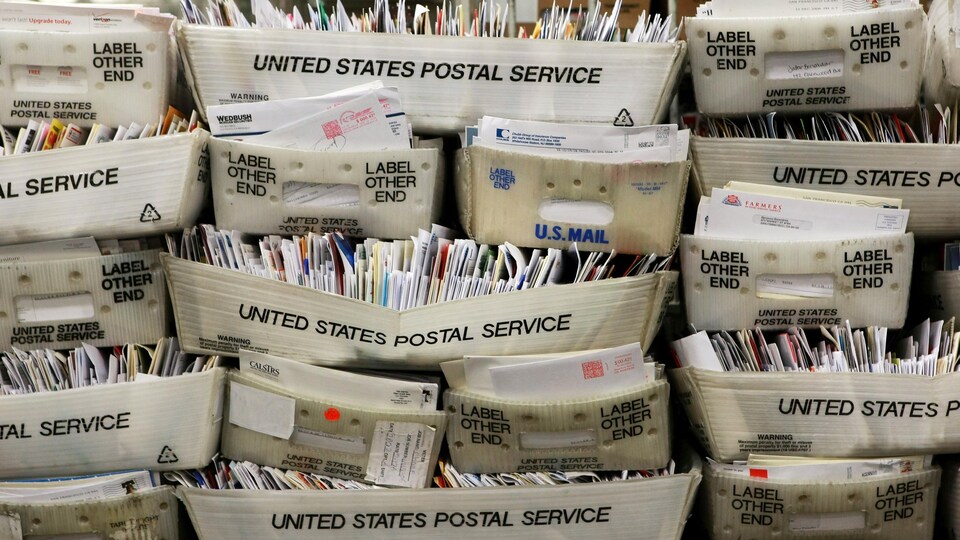 Des boîtes de courrier s'empilent dans un centre de tri.