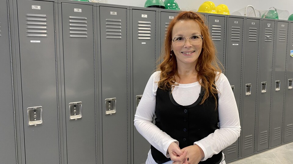 A woman poses in front of work lockers 