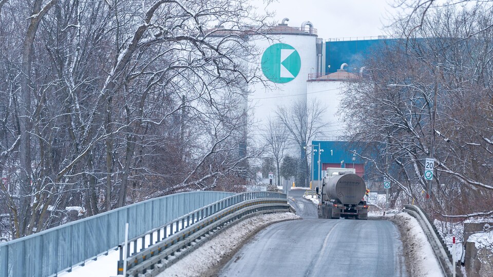 Extérieur de l'usine de papier de Kruger en hiver, avec un camion sur la route menant à l'usine.