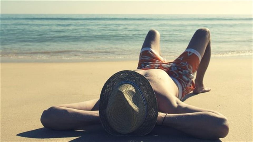 Un homme étendu au bord de l'eau sur le sable d'une plage