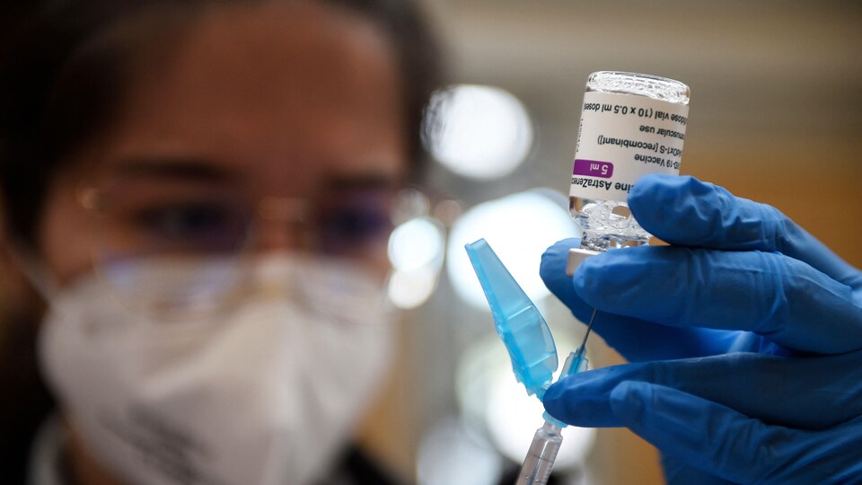 Une femme remplit une seringue à partir d'une fiole contenant le vaccin.