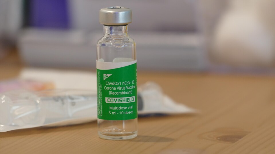 Un flacon du vaccin AstraZeneca-Oxford sur une table en bois.