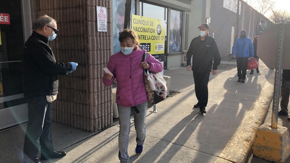 Une dame reçoit un coupon pour réserver sa dose.