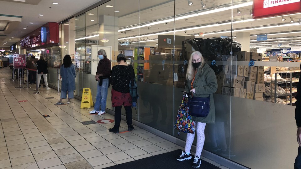 Des gens qui font la file pour entrer au Shoppers.