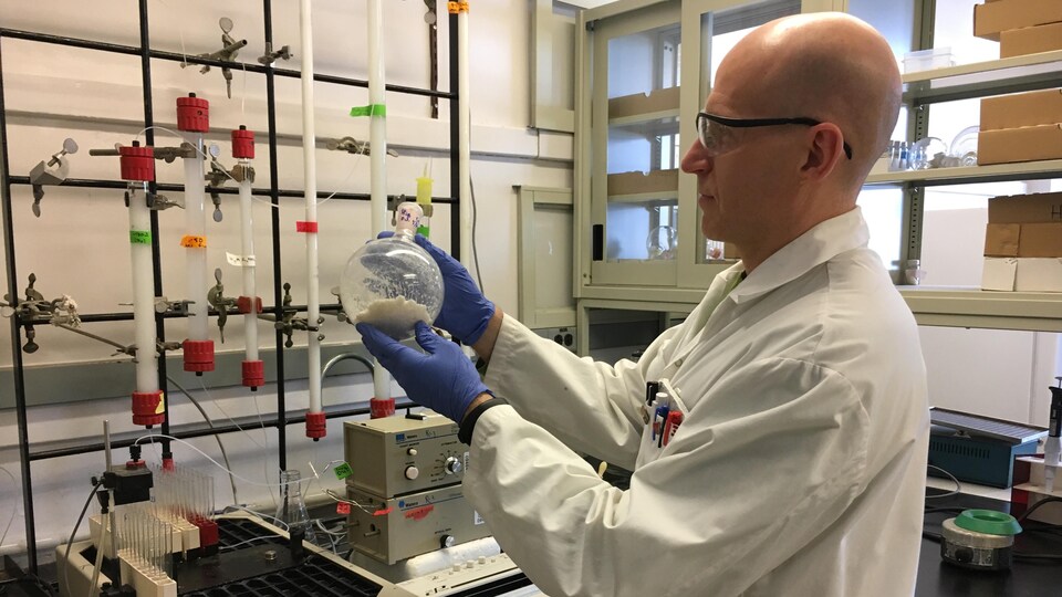 Frank St. Michael montre une fiole dans un laboratoire.
