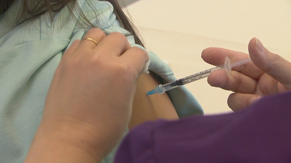 Une infirmière administre une dose de vaccin à une personne.