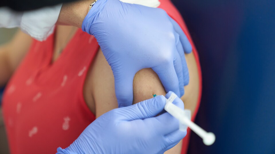 Une femme se fait vacciner sur le bras gauche.
