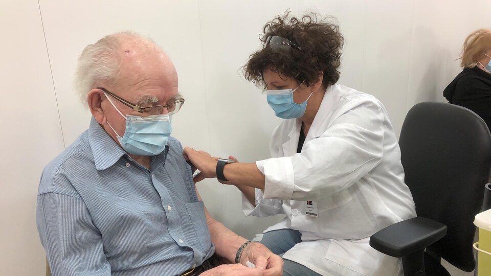 Une infirmière en train de vacciner un homme âgé.