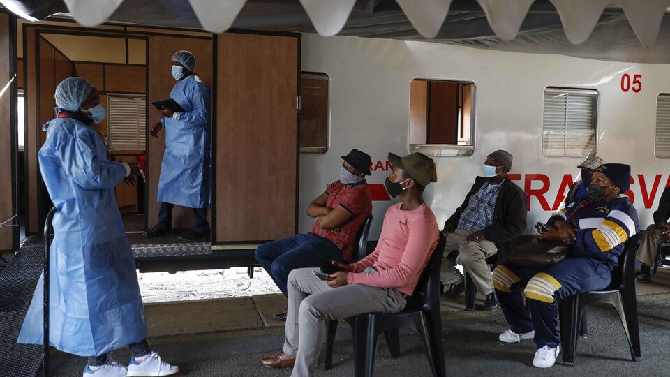 Un travailleur de la santé, debout, s'adresse à des patients assis devant lui lors d'une clinique de vaccination contre la COVID-19 en Afrique du Sud.