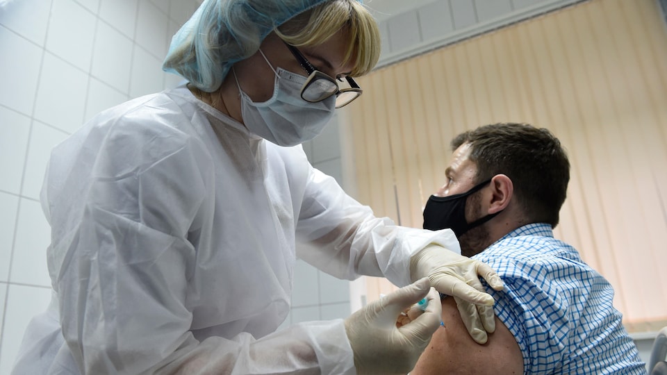 Une infirmière russe vaccine un homme.