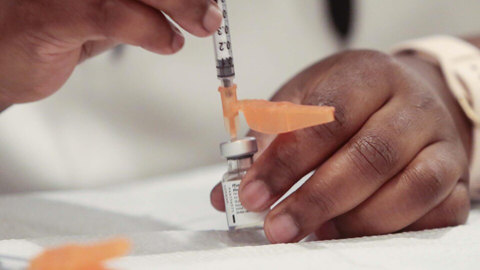 Une aiguille est introduite dans une fiole de vaccin.
