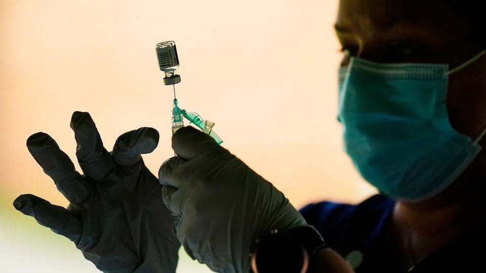 Employé de la santé tenant une seringue et une fiole de vaccin.