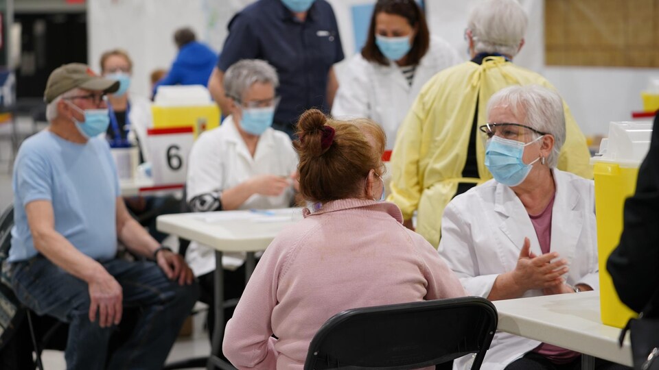 Des employés avec masque et lunettes qui s'apprêtent à vacciner des citoyens à Louiseville.