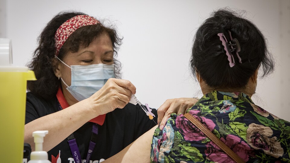 Une femme se fait injecter le vaccin dans l'épaule.