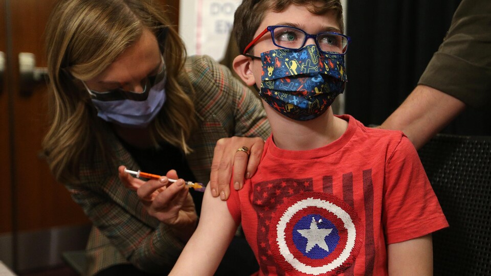 Un garçon se fait injecter le vaccin pédiatrique contre la COVID-19 dans l'épaule.