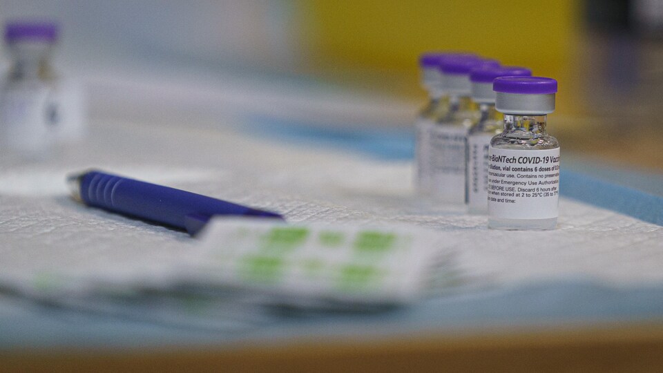 Des fioles du vaccin de Pfizer sont posées sur une table.